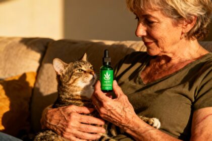 Femme de 55 ans tenant doucement un chat souffrant d'arthrose près d'une bouteille d'huile CBD verte